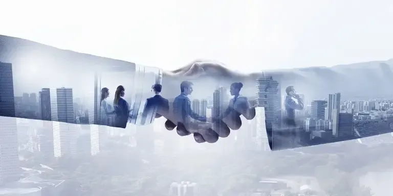 Double exposure of a business handshake over a city skyline with silhouettes of professionals in suits