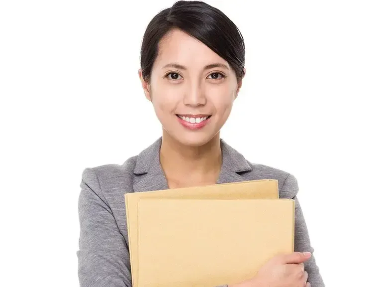 Smiling woman in a gray blazer holding a manila folder against a white background