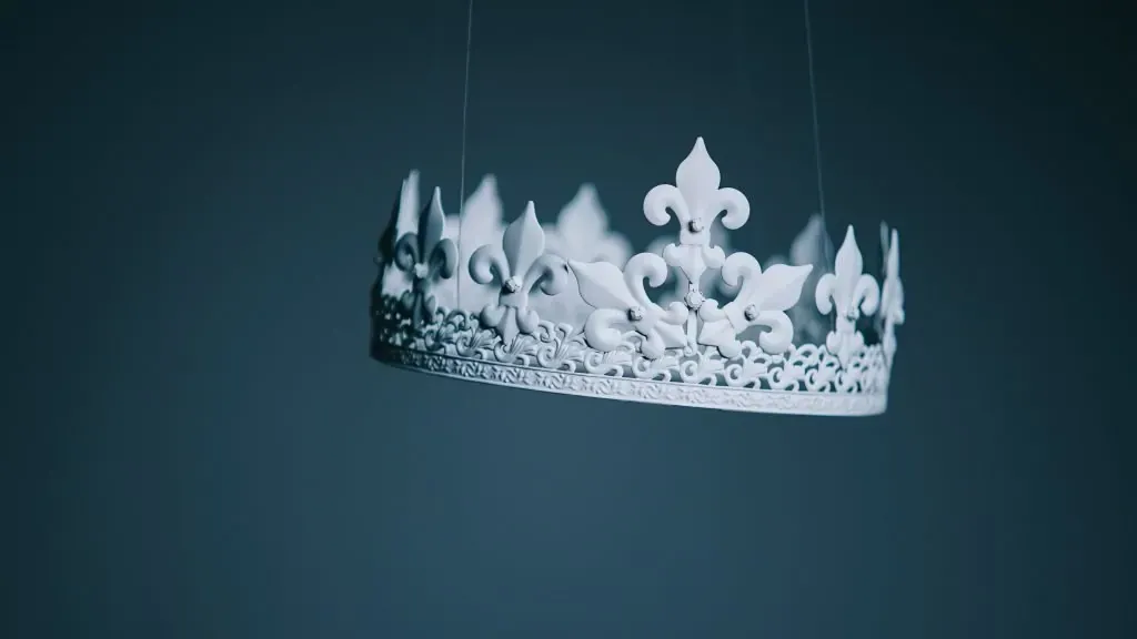 Ornate white crown with fleur-de-lis points suspended by thin wires against a dark blue background