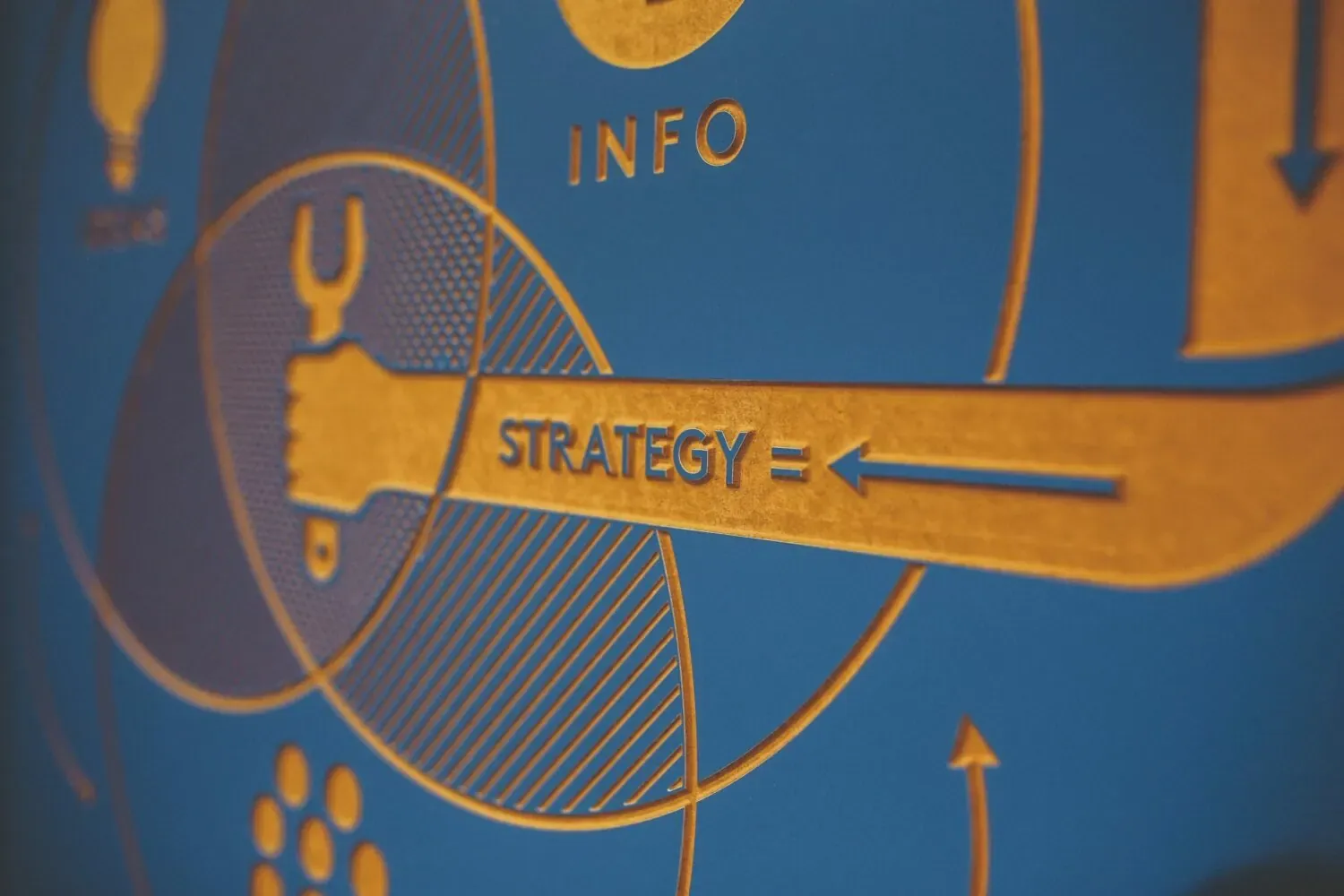 Close-up of orange and blue printed infographic with the words STRATEGY and INFO, arrows, and circles