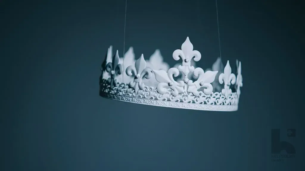 Ornate white crown with fleur-de-lis points suspended by thin wires against a dark blue background