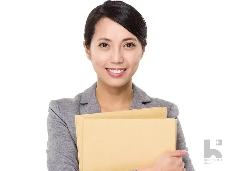 Smiling woman in a gray blazer holding a manila folder against a white background